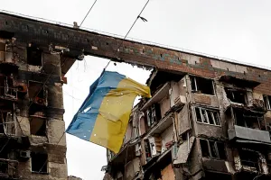 флаг України перед зруйнованим домом